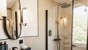 A modern bathroom with a glass-enclosed shower, a large mirror, and a vanity with a sink and towel rack. - Thegreatnorth - Holstentherme Resort Hotel (Kaltenkirchen)