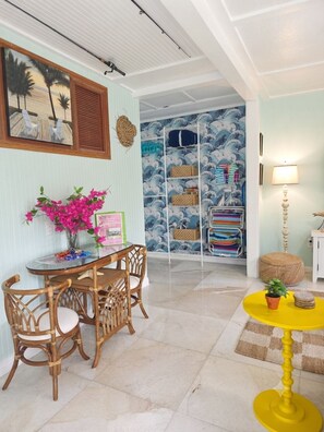 A room with a dining table, chairs, a yellow stool, a lamp, and a wall with a blue and white pattern. - Bougainvillea Villa #3. 2 blocks to downtown LWB and 1 mile to beach
 PETS OK! (Lake Worth Beach)