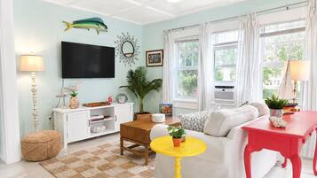 Ein Wohnzimmer mit Sofa, Couchtisch, Fernseher und Deckenventilator.