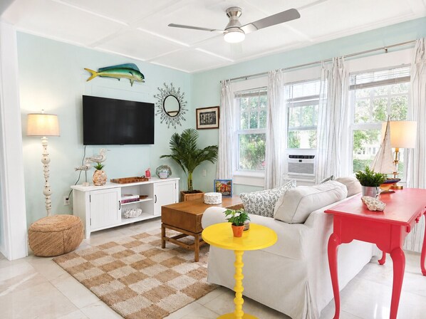 A living room with a sofa, a coffee table, a TV, and a ceiling fan. - Bougainvillea Villa #3. 2 blocks to downtown LWB and 1 mile to beach
 PETS OK! (Lake Worth Beach)