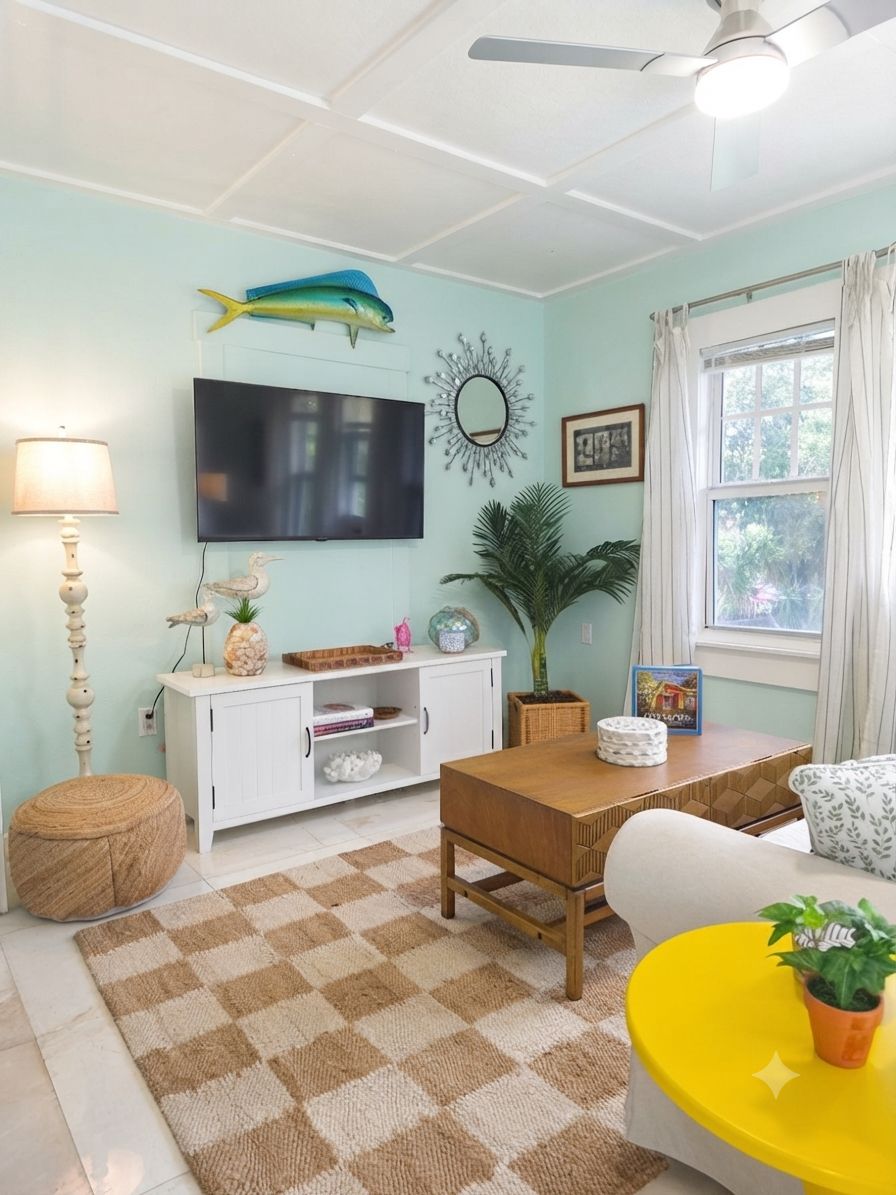 A living room with a television, a wooden table, a sofa, a lamp, and a window with curtains.