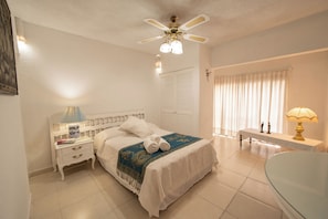 A hotel room with a bed, bedside tables, a ceiling fan, a window with curtains, and a bathroom area. - Casa Helen Your retreat in Cuernavaca (Cuernavaca)