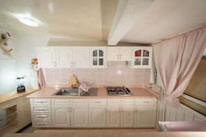 A kitchen with white cabinets, a sink, a stove, and a window with curtains. - Casa Helen Your retreat in Cuernavaca (Cuernavaca)