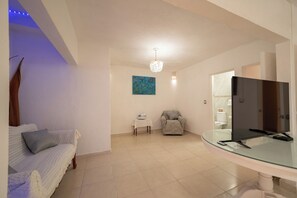 A living room with a sofa, a chair, a table with a cake, a television on a glass stand, and a painting on the wall. - Casa Helen Your retreat in Cuernavaca (Cuernavaca)