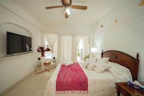 A hotel room with a bed, a television, a ceiling fan, and a window with curtains. - Casa Helen Your retreat in Cuernavaca (Cuernavaca)