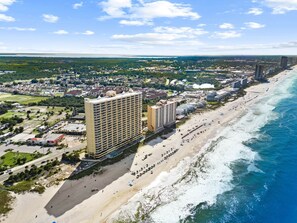 A coastal cityscape with a beachfront hotel, a marina, and a bridge in the distance. - Emerald Isle: Beachfront Condo, Pool, Balcony (Panama City Beach)