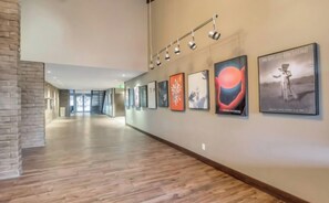 Un pasillo con suelo de madera, pared de ladrillo decorativa y varias obras de arte enmarcadas en la pared.
