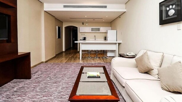 Ein modernes Wohnzimmer mit einer Couch, einem Couchtisch und einer Küche im Hintergrund.