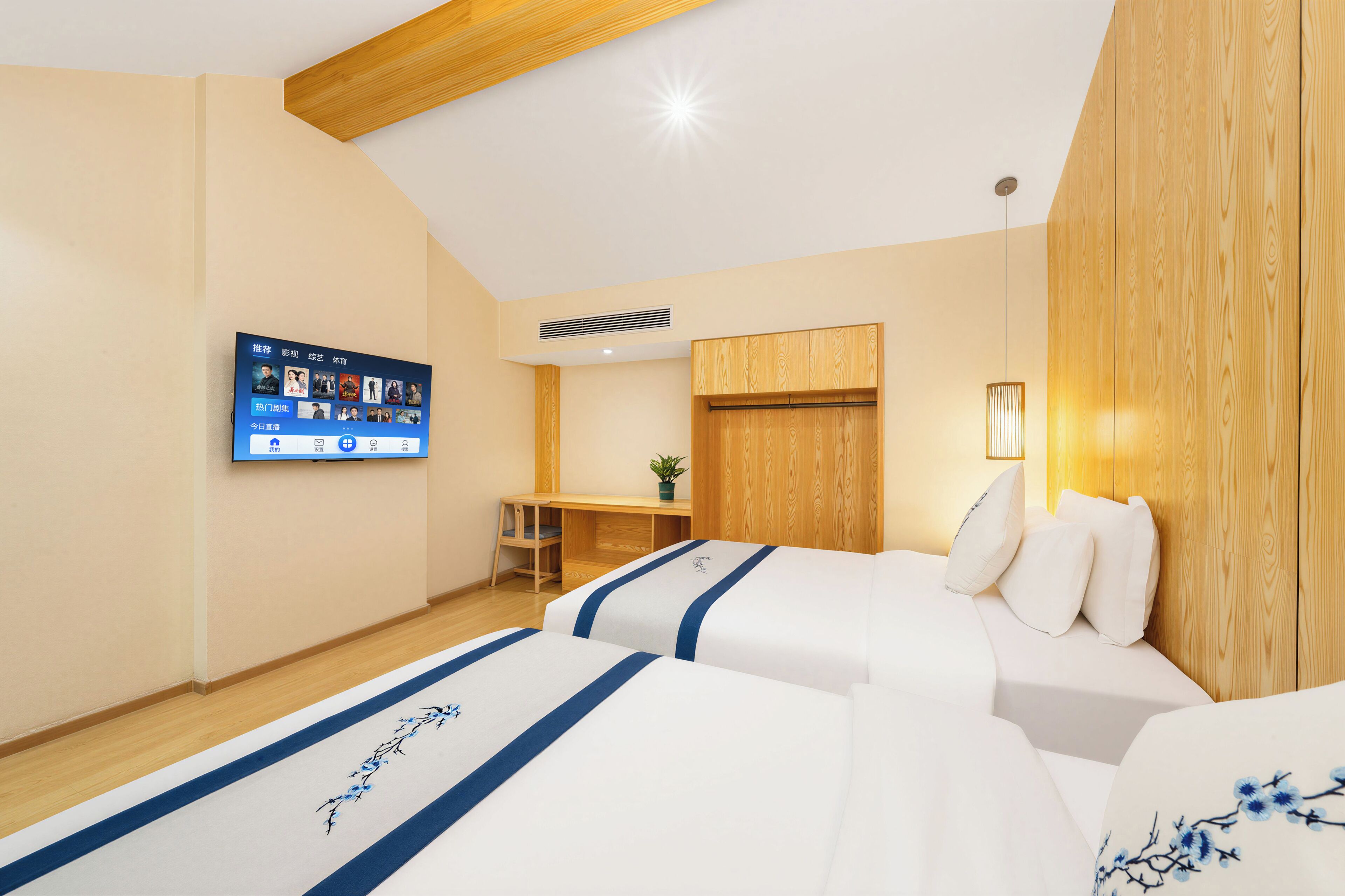 Habitación de hotel con dos camas, un escritorio, un televisor montado en la pared y un armario de madera.