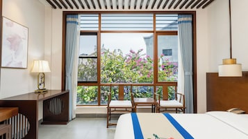 Una habitación de hotel con un ventanal grande, una cama, un escritorio y una silla.