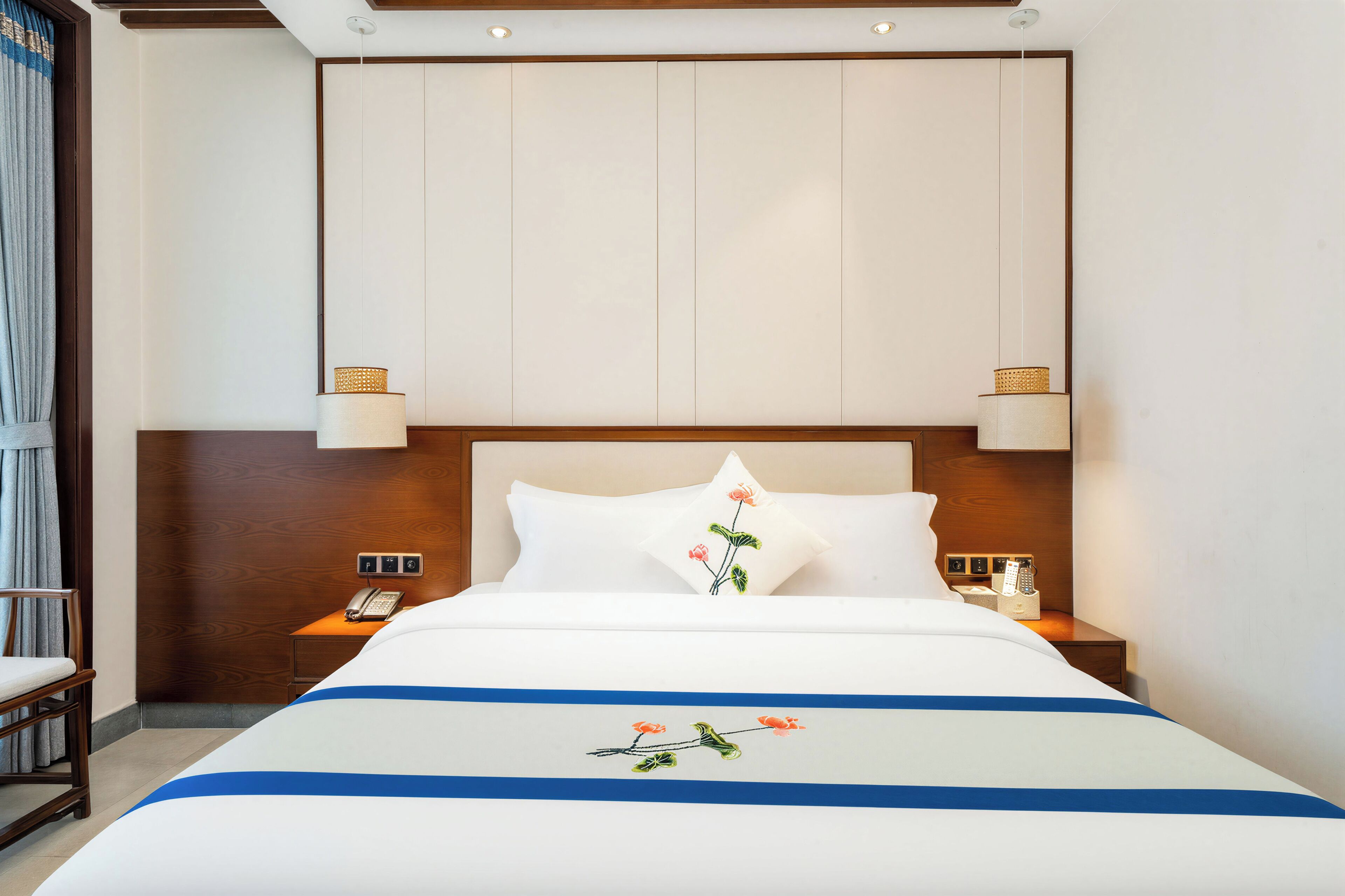 Ein Hotelzimmer mit einem großen Bett, zwei Nachttischen, einem Telefon und einer Wandleuchte.