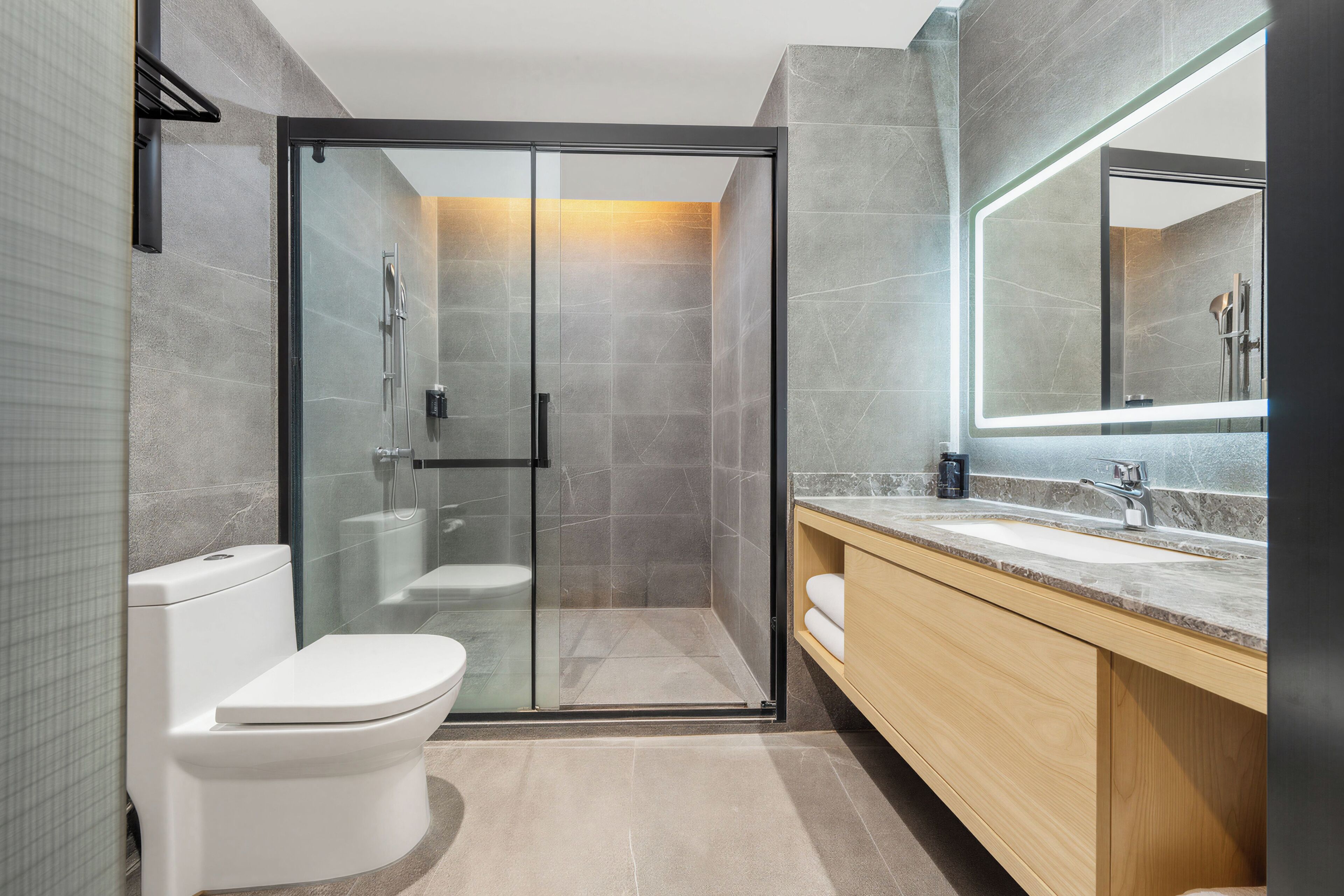 A modern bathroom with a glass-enclosed shower, a toilet, and a vanity with a sink and mirror.