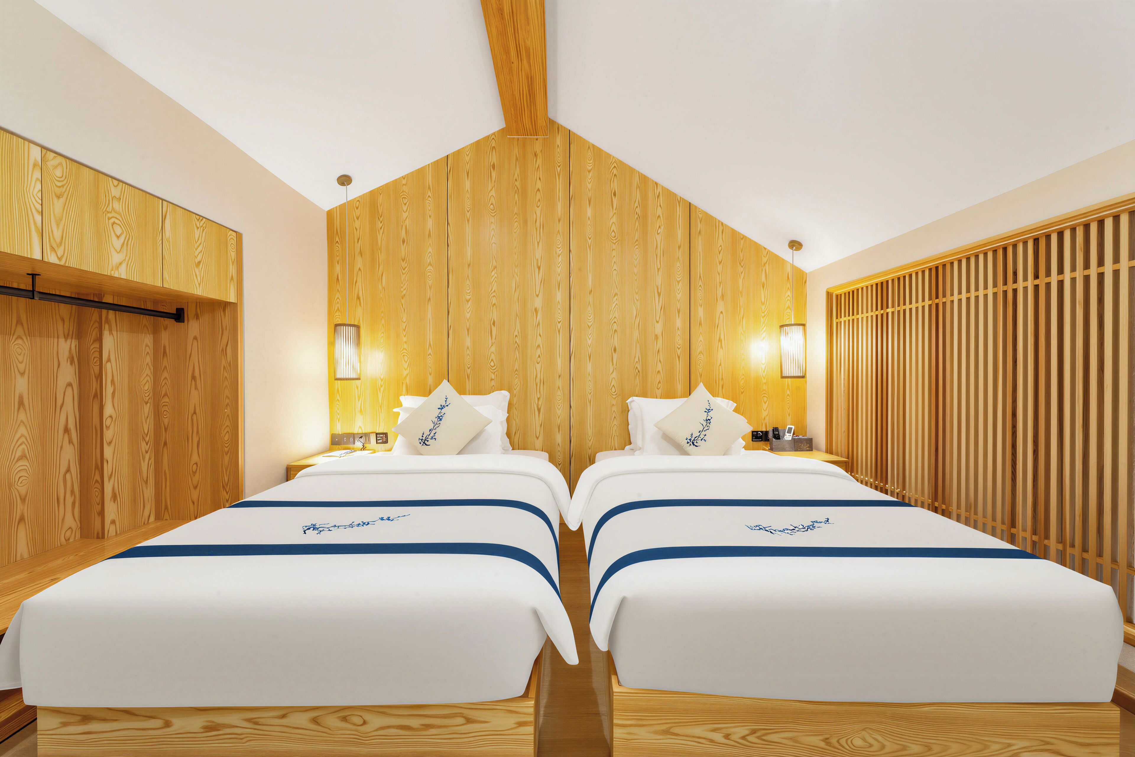 Una camera d'albergo con due letti, pannelli di legno sulle pareti e un soffitto spiovente.