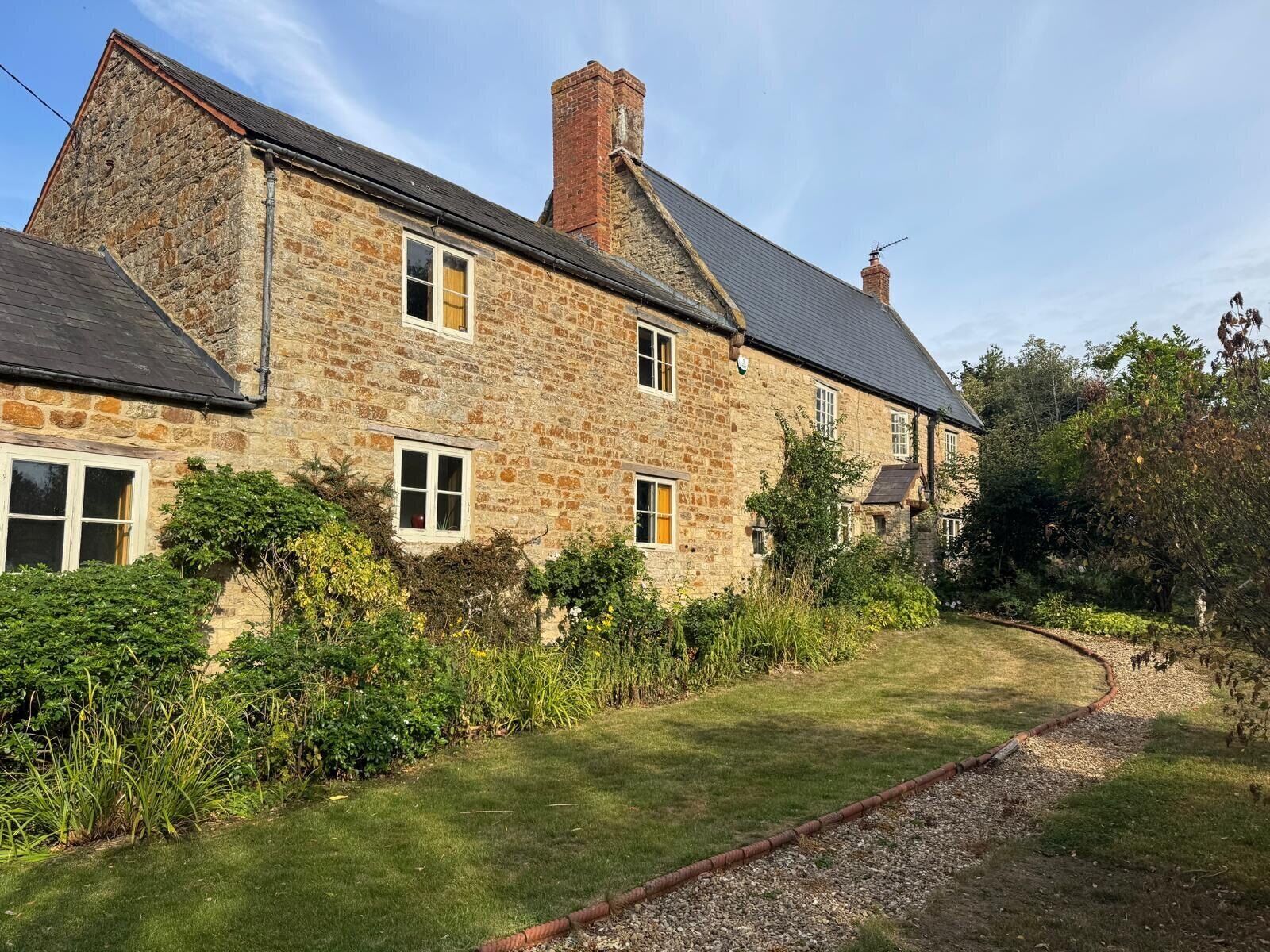 A stone house with a well-maintained lawn and a gravel path.