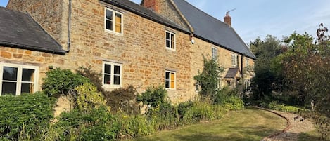 A stone house with a well-maintained lawn and a gravel path.