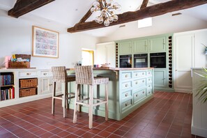 A kitchen with a central island, two bar stools, and a hanging light fixture. - 17th Century Farmhouse - Near Silverstone Circuit (Towcester)