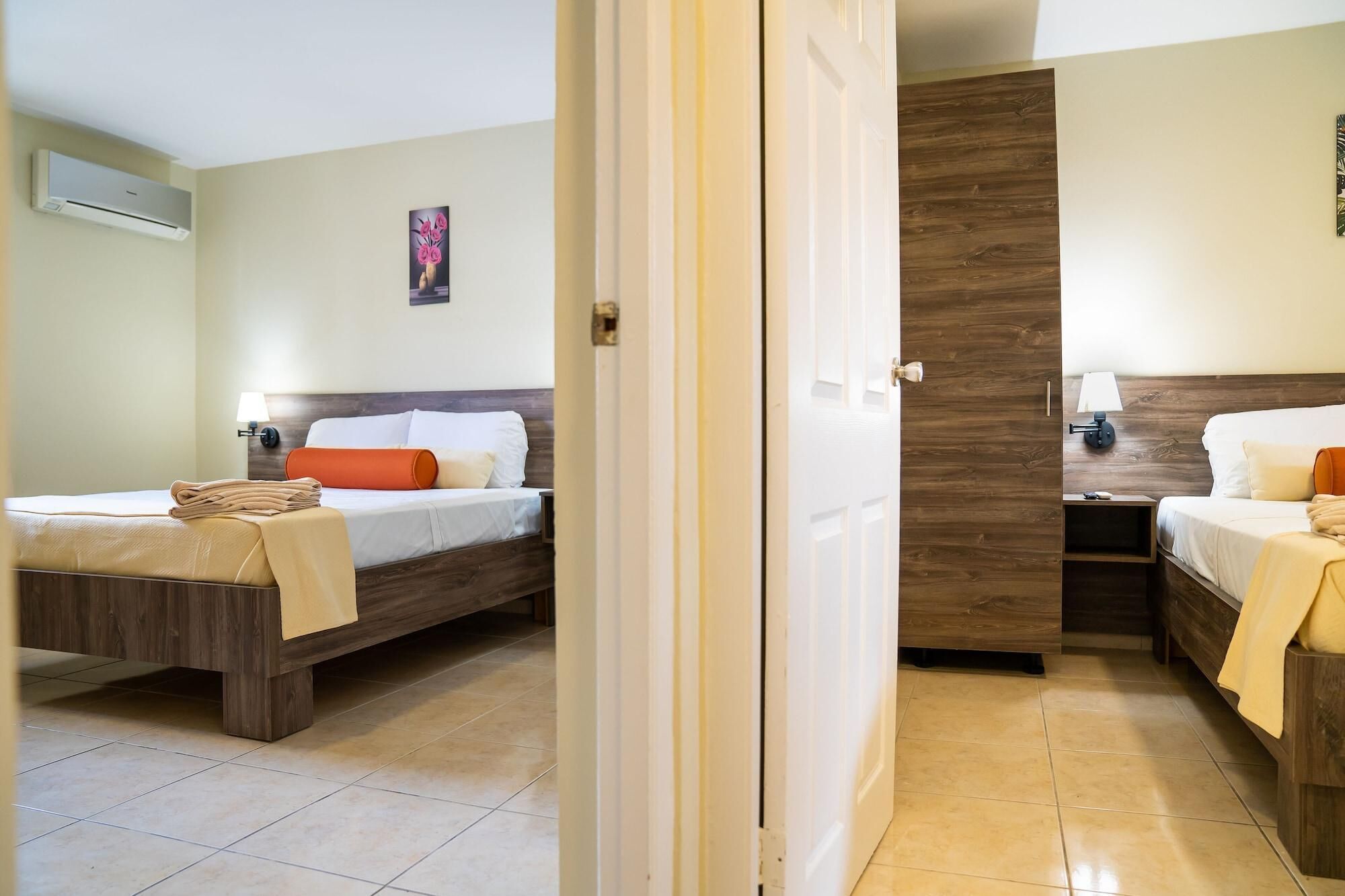 Een hotelkamer met twee bedden, een houten hoofdeinde, een schilderij aan de muur en een betegelde vloer.