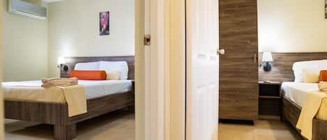 A hotel room with two beds, a wooden headboard, a painting on the wall, and a tiled floor.