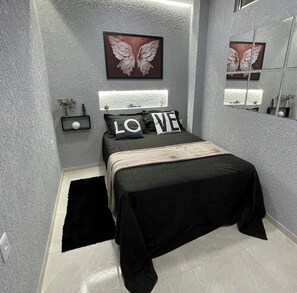 A modern bedroom with a bed, a nightstand, a mirror, and decorative wall art. - Apartment in Copacabana Inhangá. In the best location in Rio de Janeiro, Copacabana. (Rio de Janeiro)