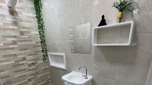Een moderne badkamer met toilet, wastafel en douche.