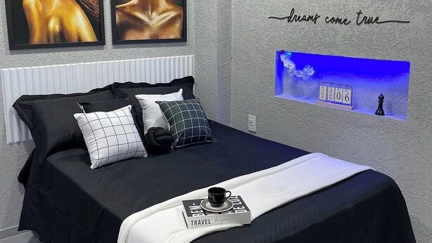 Een moderne slaapkamer met een bed, kussens, een lijst met kunstwerk, een wandklok en een inspirerende quote.