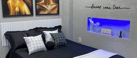 Un dormitorio moderno con una cama, almohadas, una obra de arte enmarcada, un reloj de pared y una frase motivacional.
