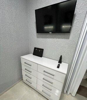A bathroom with a white vanity, a mounted TV, and a black bottle on the counter. - Apartment in Copacabana Inhangá. In the best location in Rio de Janeiro, Copacabana. (Rio de Janeiro)