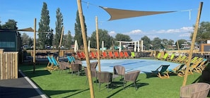 Ein Außenpoolbereich mit Liegestühlen und einem schattigen Platz.