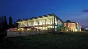 Ein modernes Gebäude mit Glasfassade, einer überdachten Außenfläche und einer umzäunten Grundstücksgrenze.