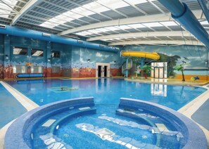 An indoor swimming pool with a hot tub, slides, and a mural of a tropical scene. - Billing Aquadrome Holiday Park - 2 Bedroom, Silver (Northampton)
