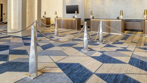 Eine Hotelhalle mit einer Rezeption, einer großen Säule und einem gemusterten Teppich.