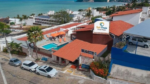 Ein Hotel mit Swimmingpool, Parkplatz und Meerblick.