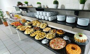 A buffet with various dishes and a selection of white cups and plates. - Sol Praia Ponta Negra (Natal)