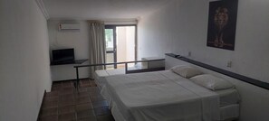 A hotel room with a bed, a desk, a television, and a window with curtains. - Sol Praia Ponta Negra (Natal)