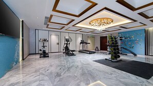 Un gimnasio moderno con equipo de ejercicio, piso de mármol y un decorativo revestimiento de pared.