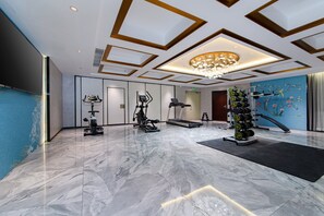 Un gimnasio moderno con equipo de ejercicio, piso de mármol y un decorativo revestimiento de pared.