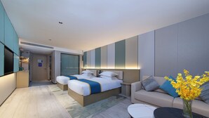 Una habitación de hotel moderna con una cama grande, un sofá, una mesa de centro y un televisor.