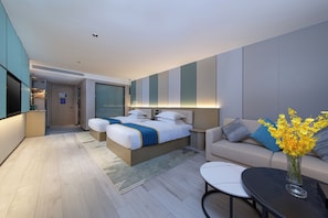 Una habitación de hotel moderna con una cama grande, un sofá, una mesa de centro y un televisor.