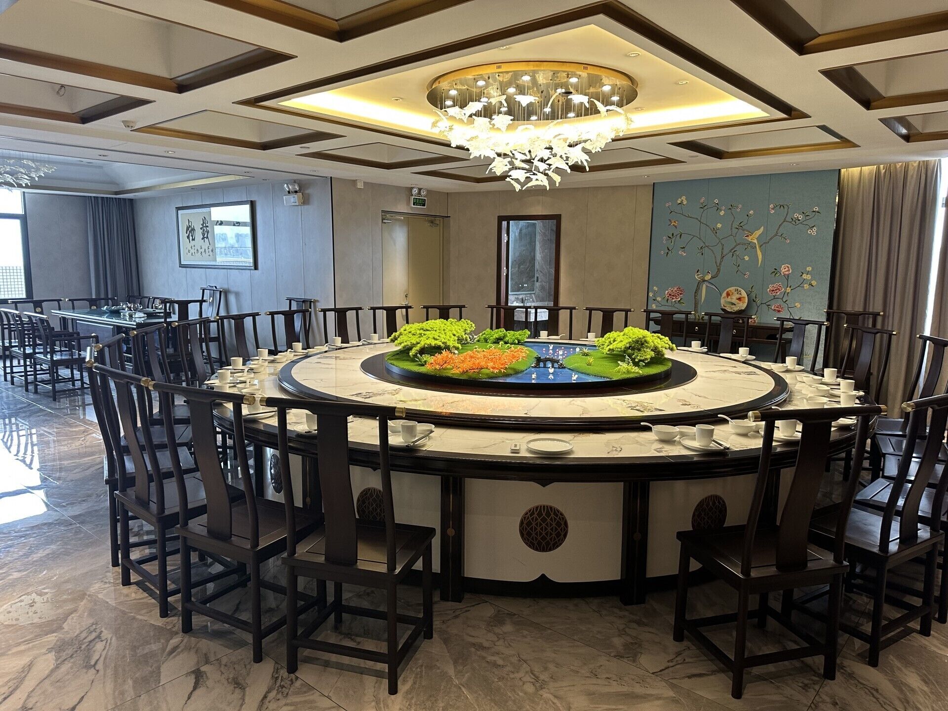 A round dining table with chairs, a chandelier, and a decorative centerpiece.