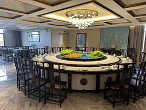 A round dining table with chairs, a chandelier, and a decorative centerpiece. - Ya Duo Hotel (Dongguan)