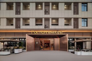 A hotel entrance with a modern facade, a signboard, and outdoor seating. - Homtel by Poltton (Xiamen Airport Huoju Garden Metro Station) (Xiamen)