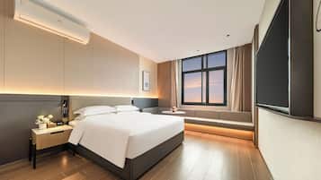 Una habitación de hotel moderna con una cama grande, una mesita de noche y un televisor.