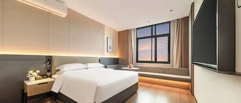 A modern hotel room with a large bed, bedside table, and a TV.
