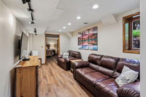 A modern living room with a leather sofa, wooden coffee table, and a painting on the wall. - Lakefront 4BR/3.5BA retreat with beautiful views (Oakland)