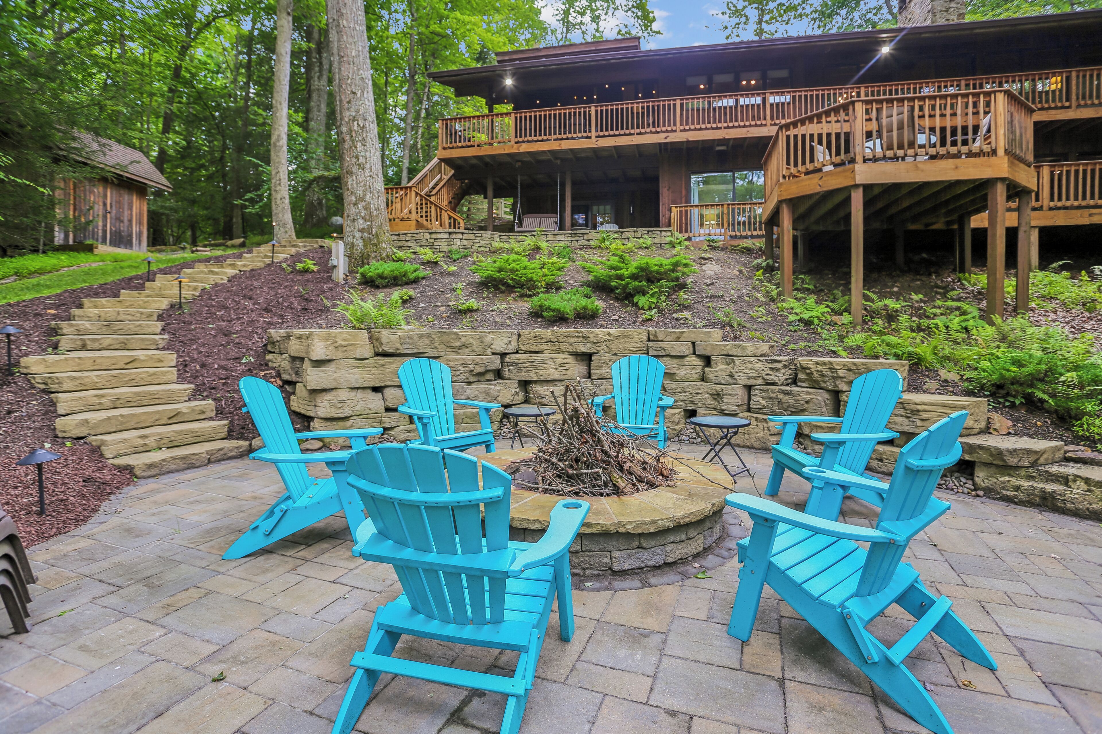 Une terrasse dotée de fauteuils Adirondack, d’un foyer en pierre et d’un mur de soutènement en pierre.