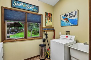 A laundry room with a large window, a sign for 'Shoes & Boots', a painting of a skier, and a washing machine. - Lakefront 4BR/3.5BA retreat with beautiful views (Oakland)