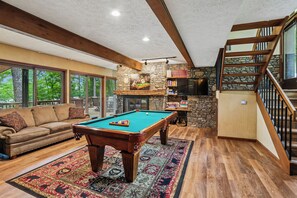A spacious living area with a pool table, a comfortable sofa, and a staircase leading to an upper level. - Lakefront 4BR/3.5BA retreat with beautiful views (Oakland)