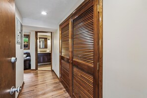 A hallway with a wooden door, a mirror, and a view into a room with a kitchen. - Lakefront 4BR/3.5BA retreat with beautiful views (Oakland)