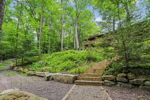 A wooden staircase leading up to a building surrounded by dense forest. - Lakefront 4BR/3.5BA retreat with beautiful views (Oakland)