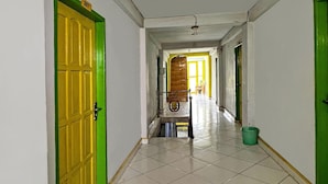 Um corredor com piso de azulejos, um banco e uma lixeira.